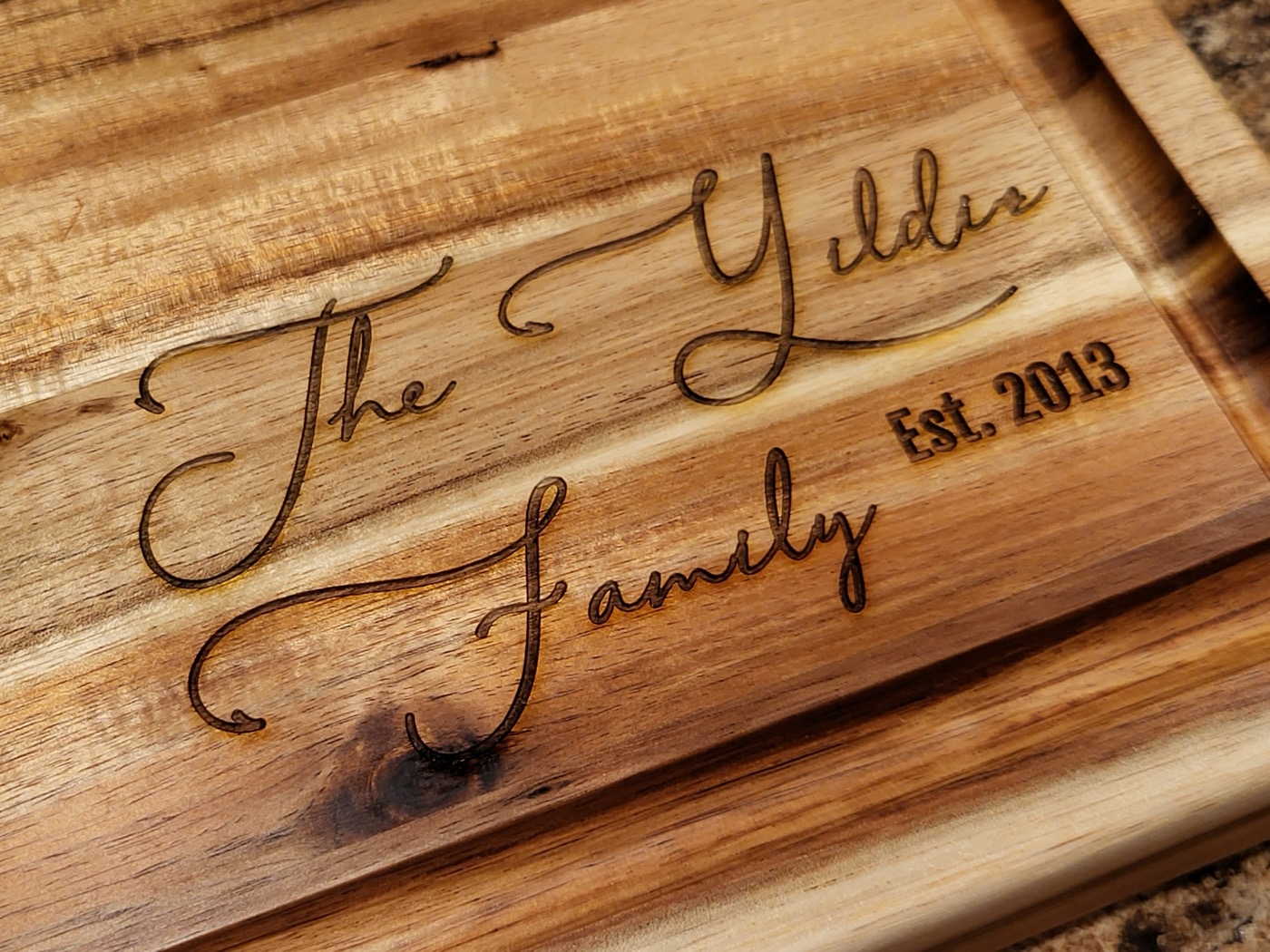A wooden cutting board engraved with the Yildiz family name